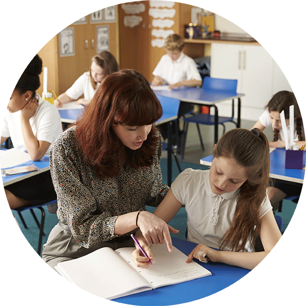 Young Female Early Careers Teacher assisting and young girl student in a classroom