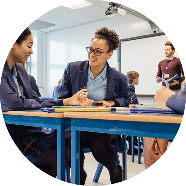 Young Female Early Careers Teacher assisting a female secondary school student